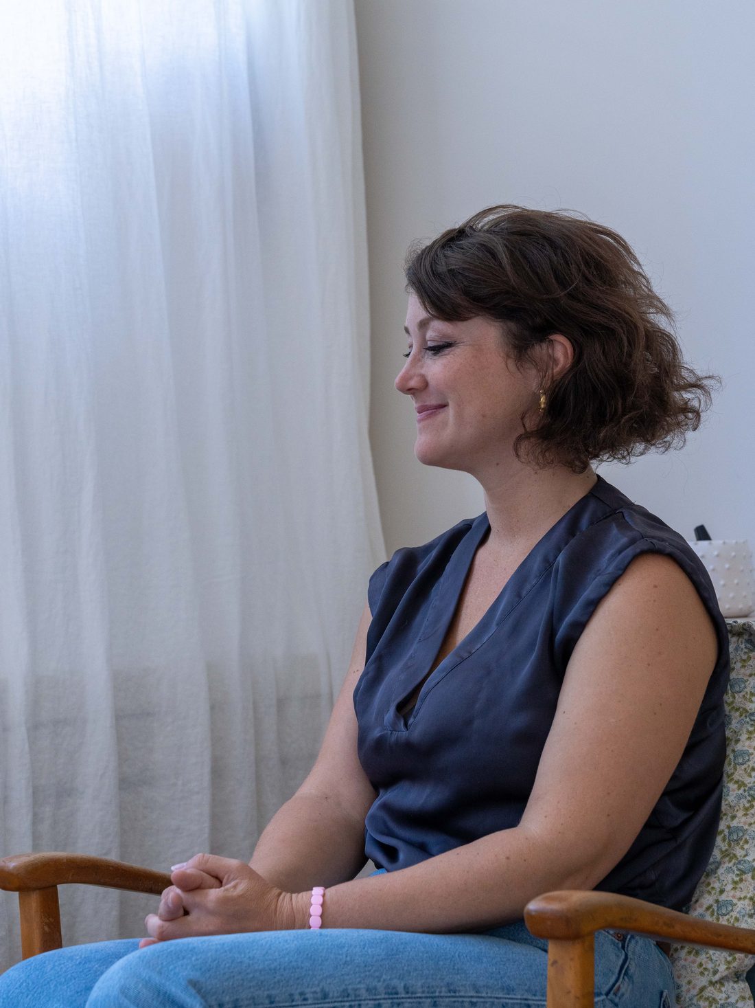 Anaïs Leneau, psychopraticienne titulaire du Certificat Européen de Psychothérapie, fondatrice d’Accès Psy UK, assise de profil dans le fauteuil de son cabinet, à l’écoute