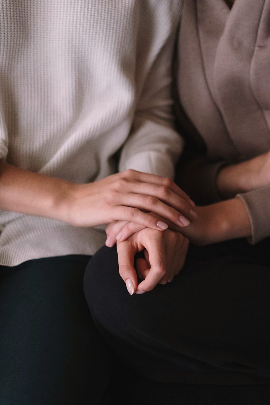 Two people sitting side by side, one hand resting on the other’s in a gesture of comfort: the social support and human connection carried by the Accès Psy UK initiative